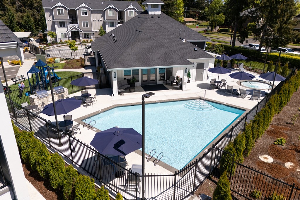 a swimming pool in front of a house with umbrellas
