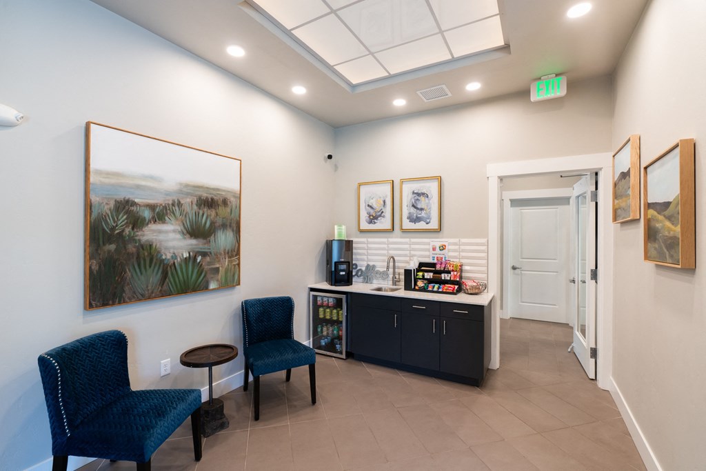 a lobby with two blue chairs and a counter with a coffee machine