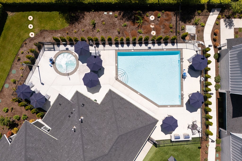 an aerial view of a swimming pool and patio with umbrellas