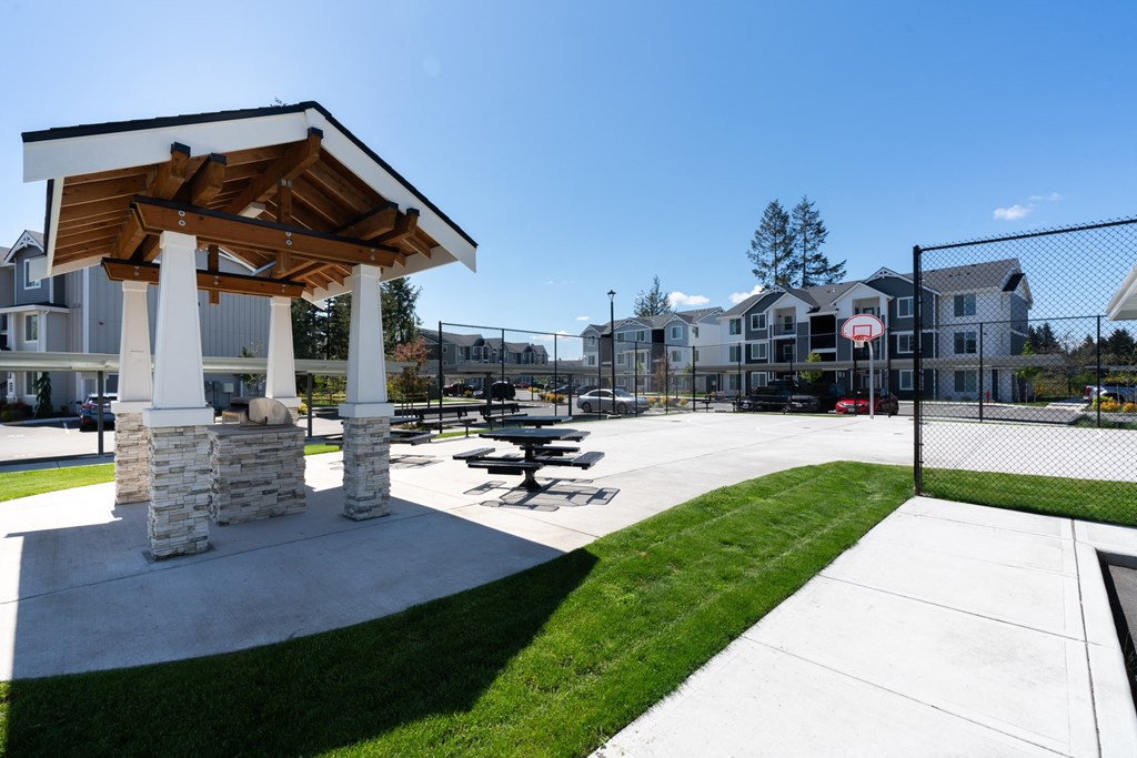a pavilion with picnic tables in a park with apartments in the background
