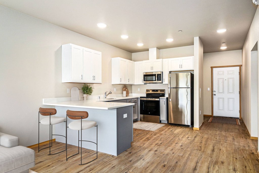 a kitchen with a white counter top and a stainless steel refrigerator