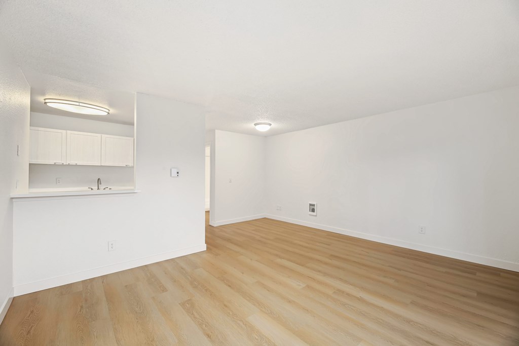 Empty room with wooden flooring and white walls.