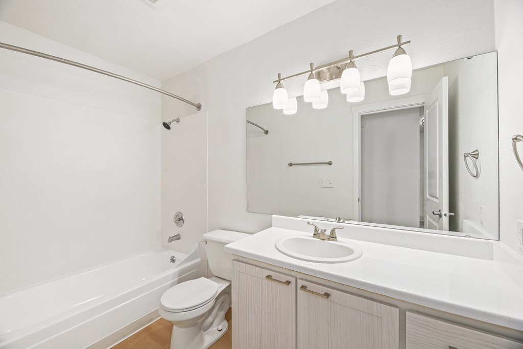 A white bathroom with a toilet, sink, and mirror.
