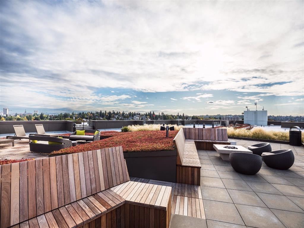 a roof top lounge area with wooden furniture and a view of the city
