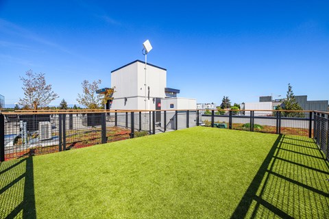 A white building with a solar panel on top is surrounded by a green fence.