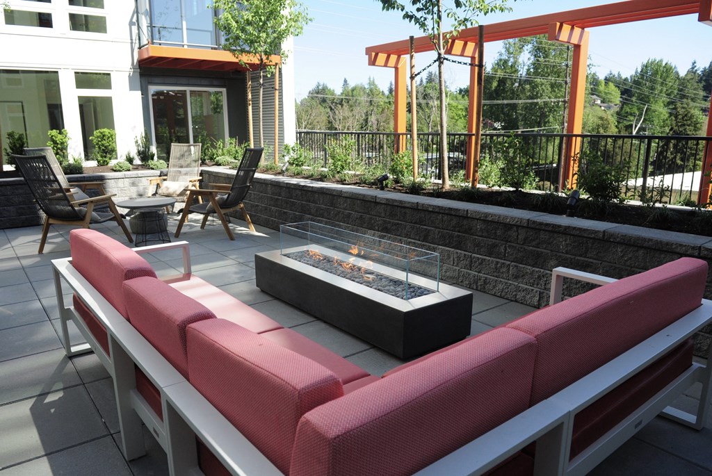 a lounge area with couches and a fire pit on a patio