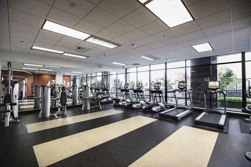 a gym with cardio equipment and windows in a building