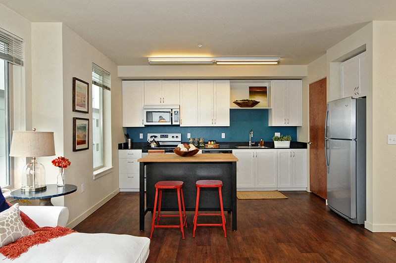 a kitchen with white cabinets and a black island with red stools