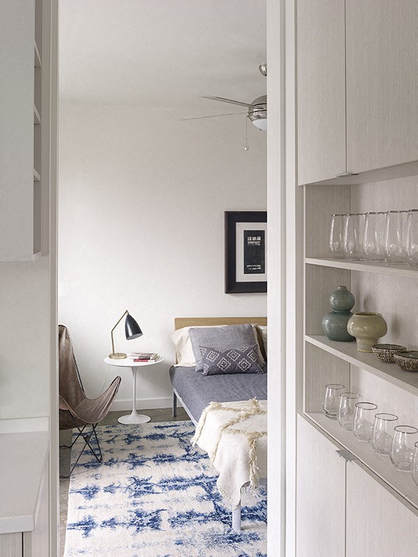 a small bedroom with a bed and a blue and white rug