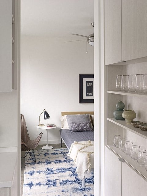 a small bedroom with a bed and a blue and white rug