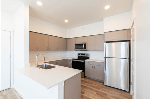 A modern kitchen with a white countertop and stainless steel appliances.
