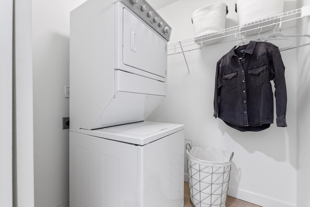 A black shirt hanging on a white wall next to a washing machine.
