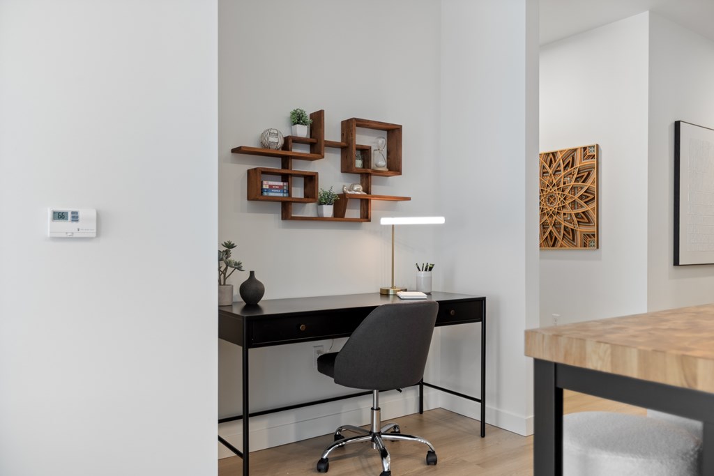 A modern home office with a black desk and a black chair.