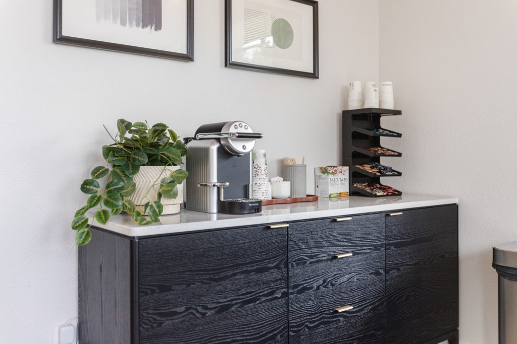 A black dresser with a plant on top and a shelf with various items.