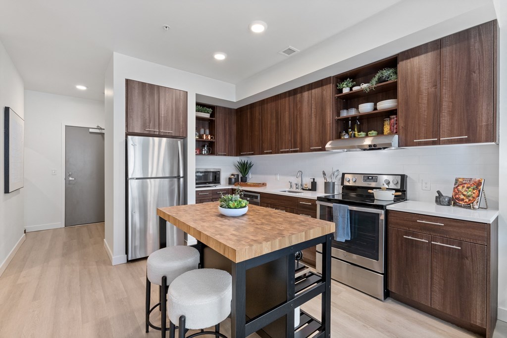 A modern kitchen with a wooden table and stools.