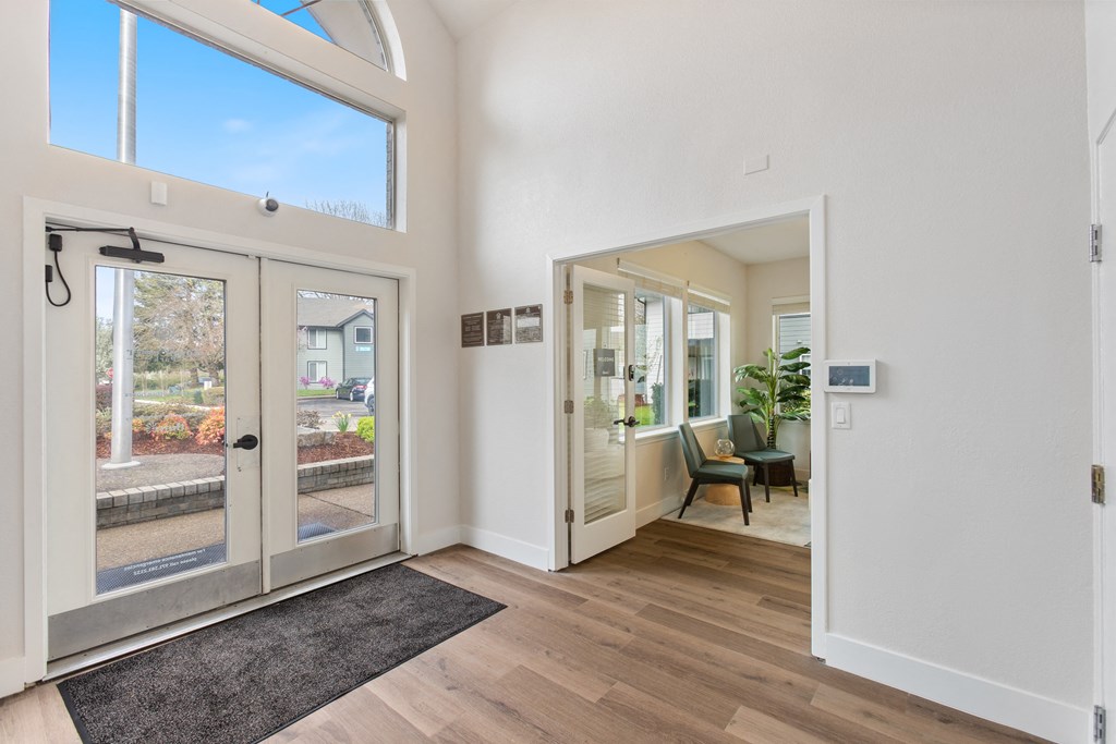 A white interior with a black rug and a glass door.