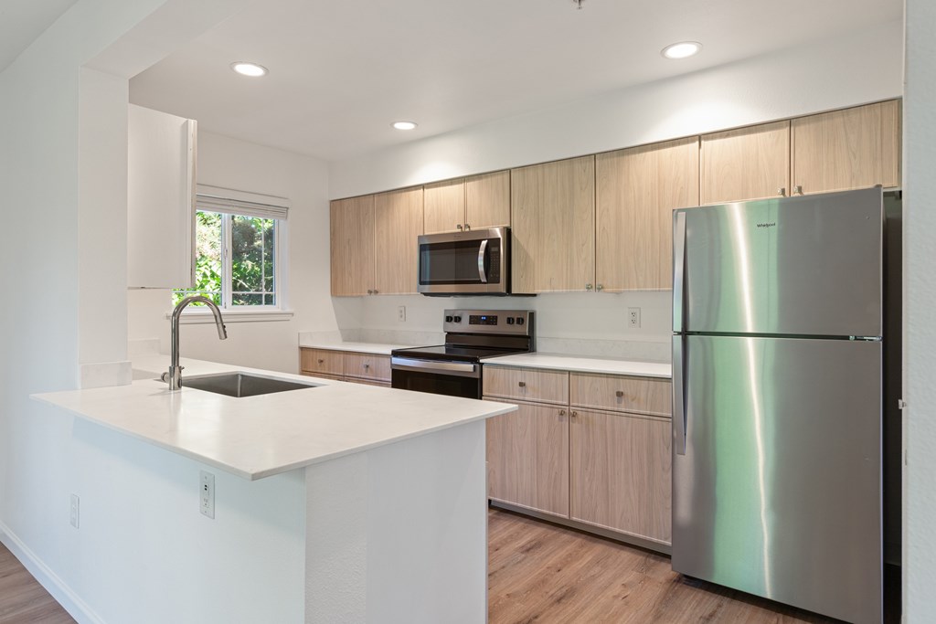 A modern kitchen with a stainless steel refrigerator and a white countertop.