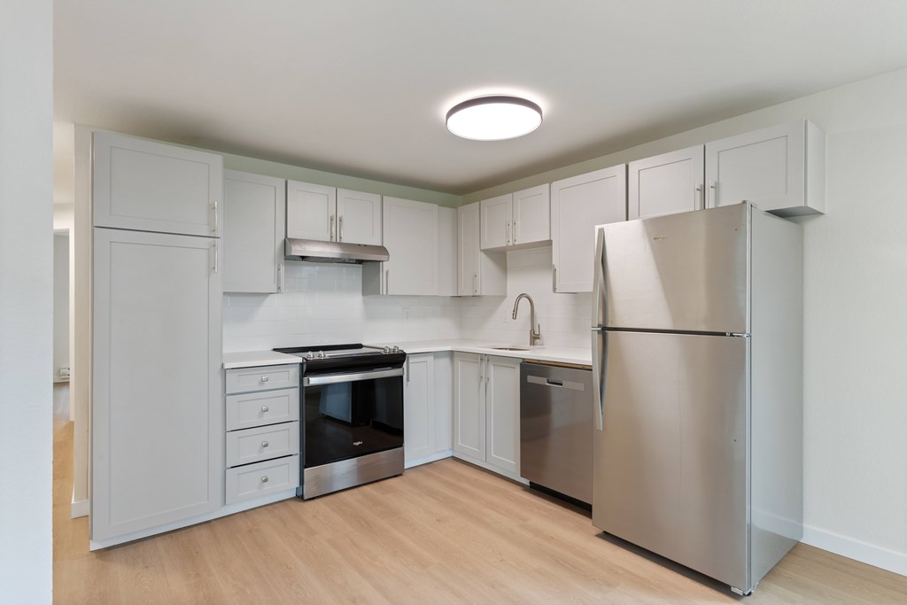 A kitchen with a refrigerator, oven, and sink.