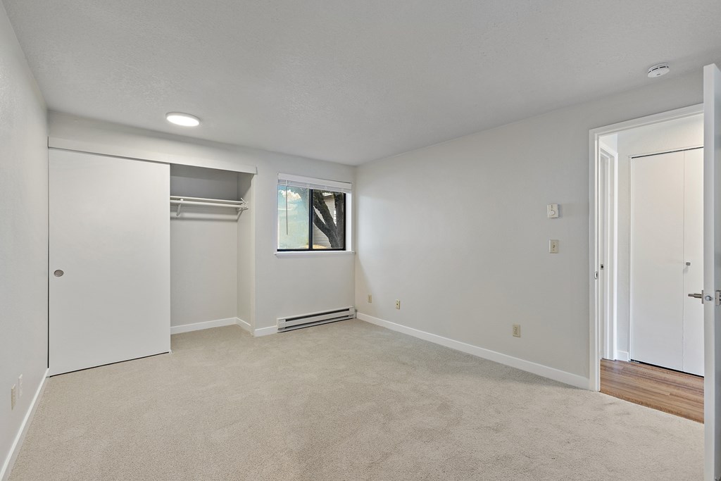 A large empty room with a window and a door.