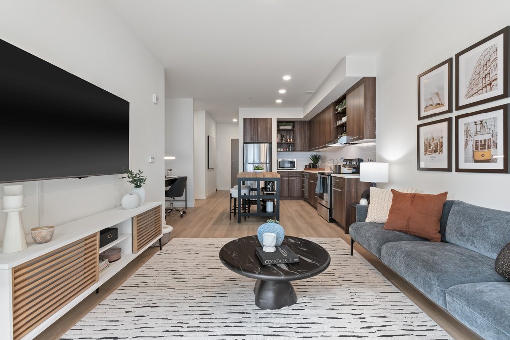 A modern living room with a grey couch and a black coffee table.