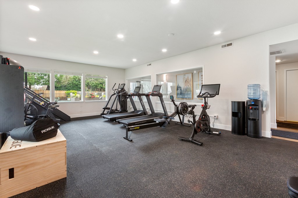 A spacious gym with a variety of equipment including treadmills, stationary bikes, and weight machines.