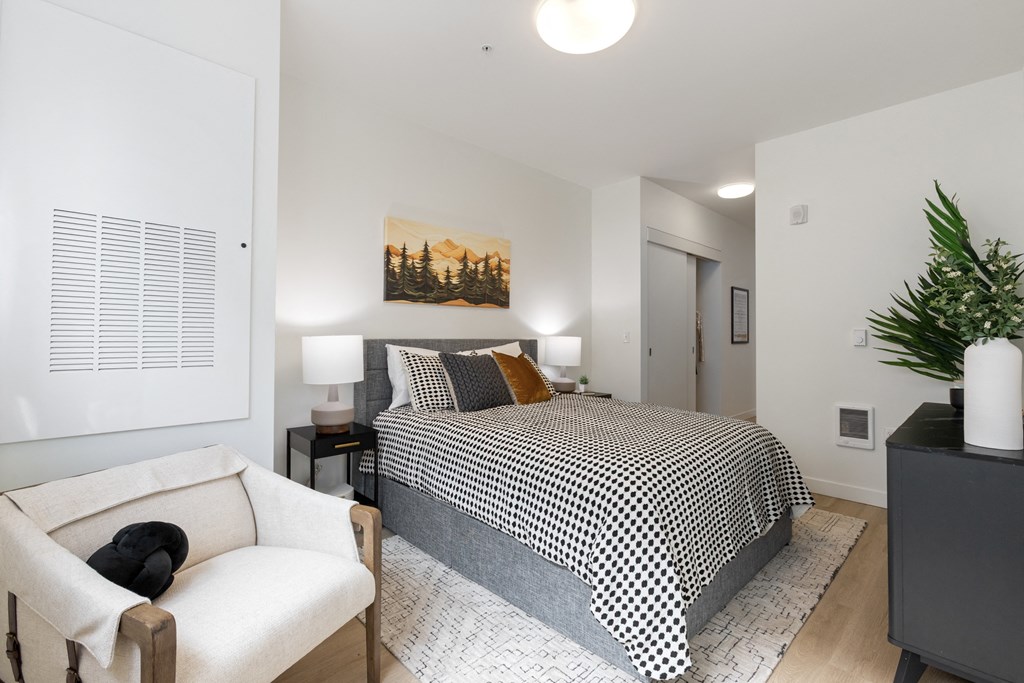 A bedroom with a bed, a chair, and a painting on the wall.