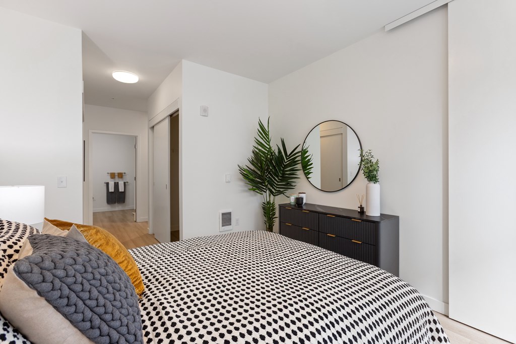 A bedroom with a bed, dresser, and mirror.