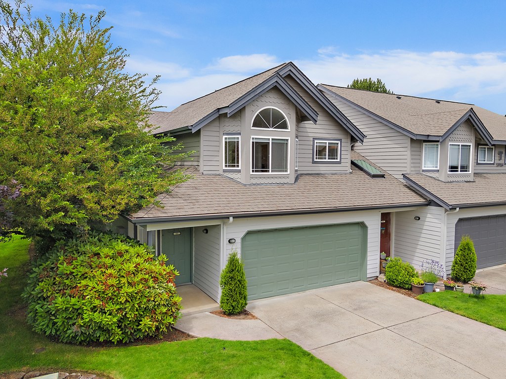 A house with a grey roof and a green garage door.