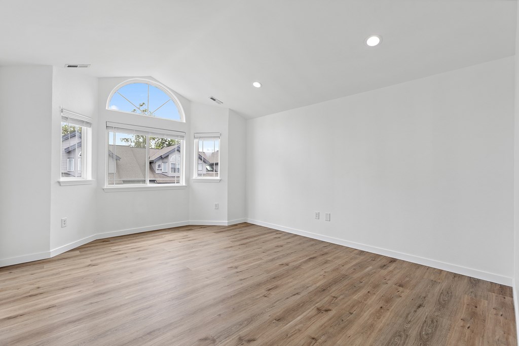 A large empty room with wooden floors and a large window.