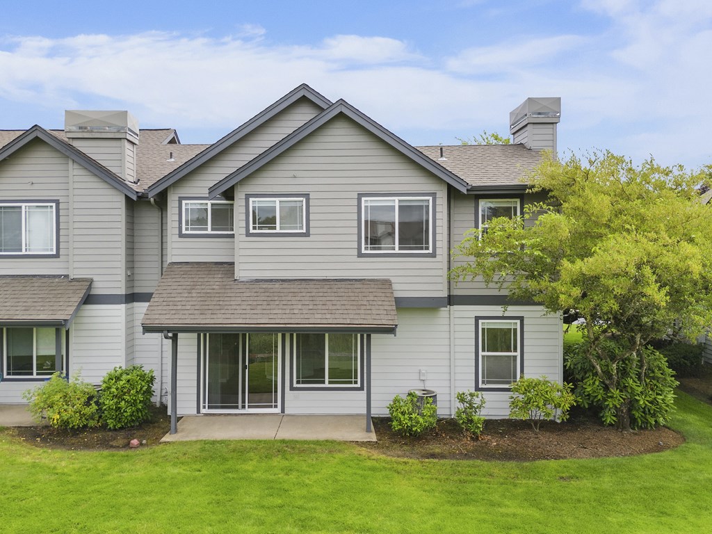 A house with a grey roof and a green lawn in front.