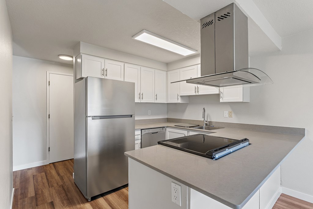 A modern kitchen with a stainless steel refrigerator and a large island with a sink.