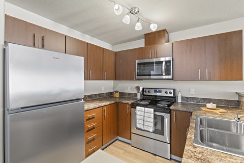 A kitchen with a stainless steel refrigerator, a stove, and a microwave.