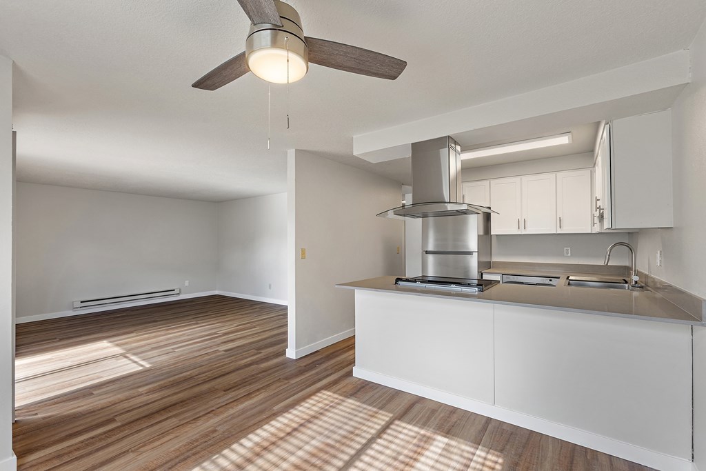 A modern kitchen with a wooden floor and white cabinets.