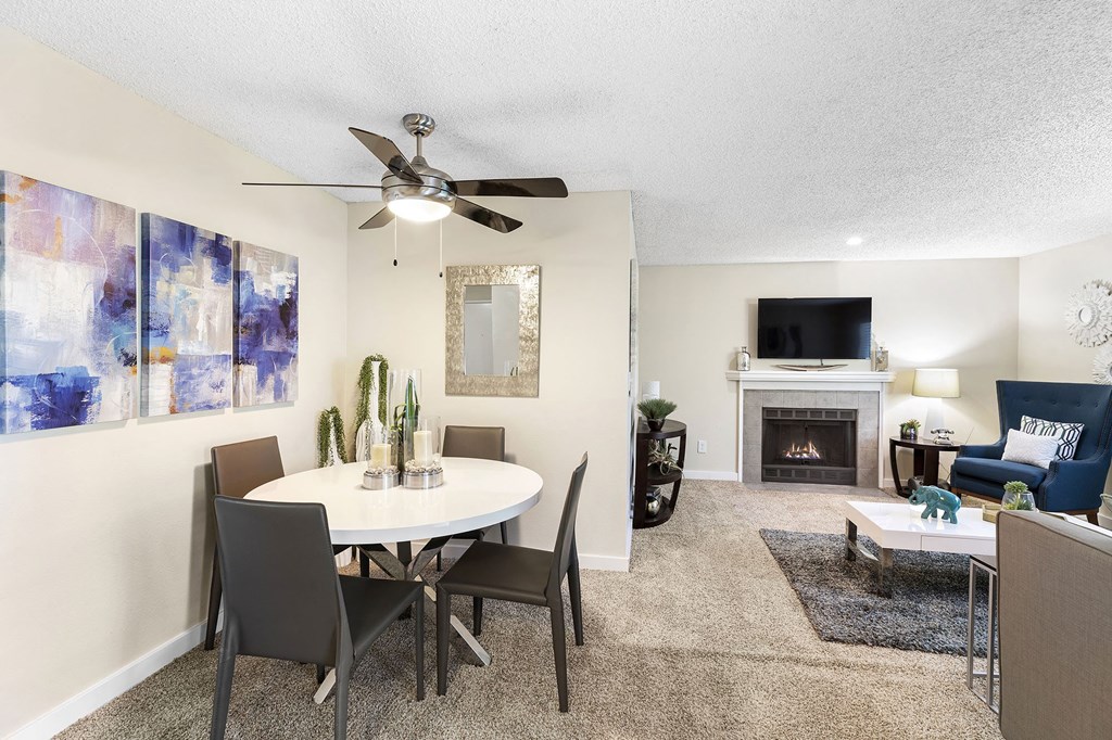a living room with a table and a ceiling fan