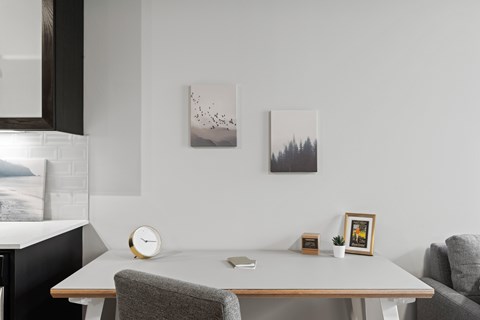 A modern dining room with a table, chairs, and pictures on the wall.