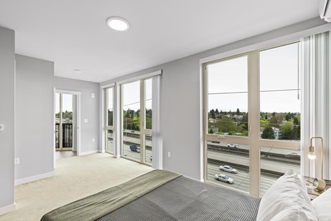 A bedroom with a large bed and a view of the highway outside.