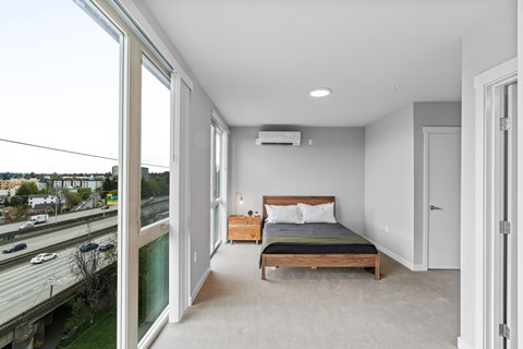 A bedroom with a large bed and a view of the highway outside.