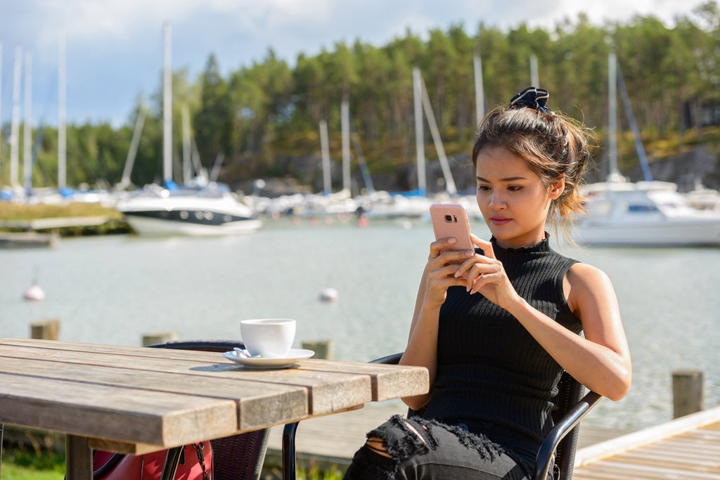a woman sitting at a picnic table looking at her cell phone