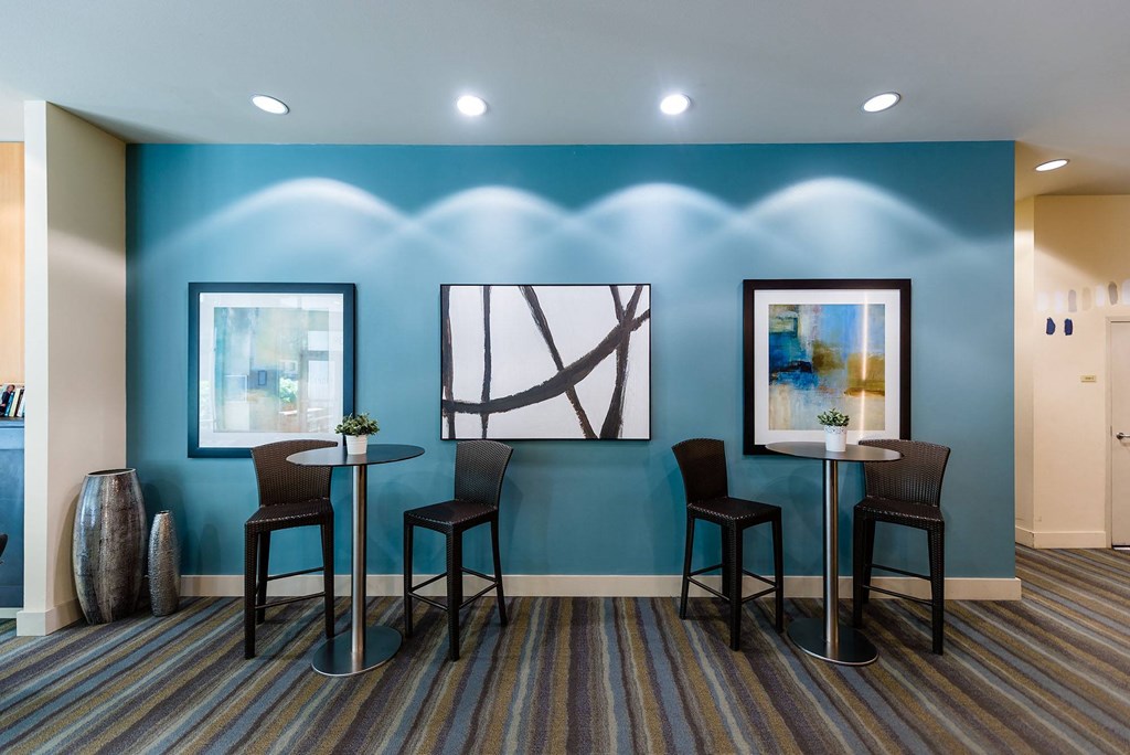 a room with two tables and three chairs in front of a blue wall