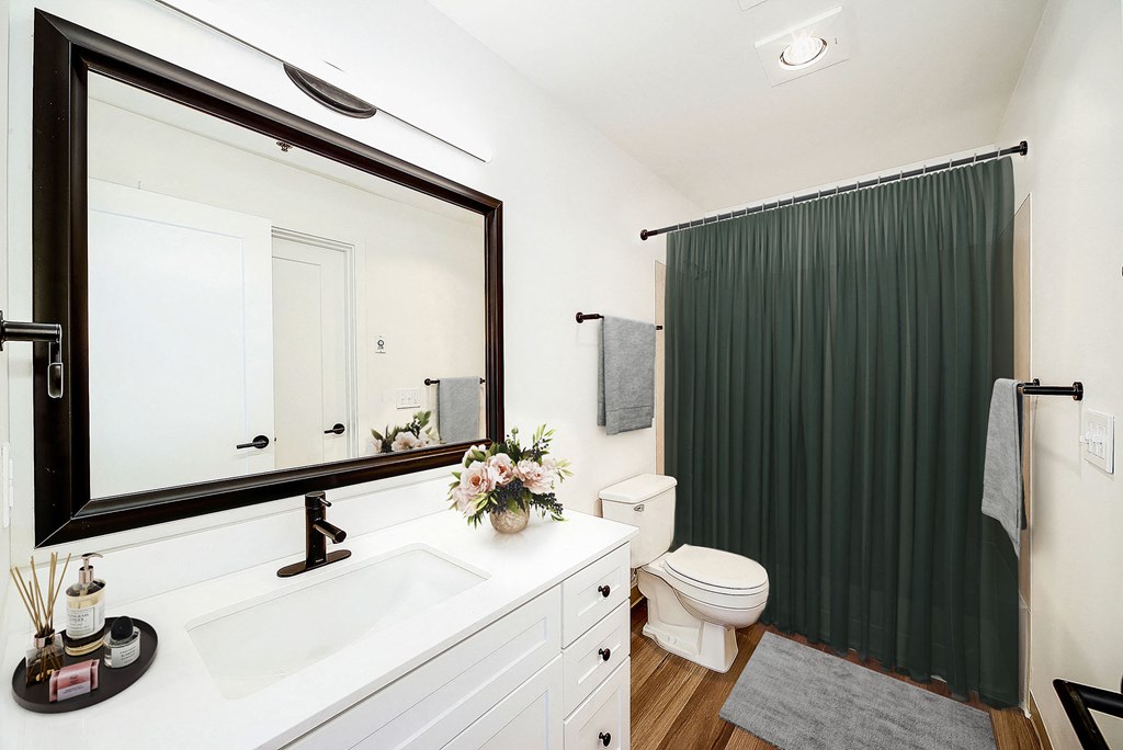 a bathroom with a white sink and toilet and a green shower curtain