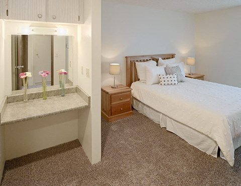 a bedroom with a bed and a counter with flowers