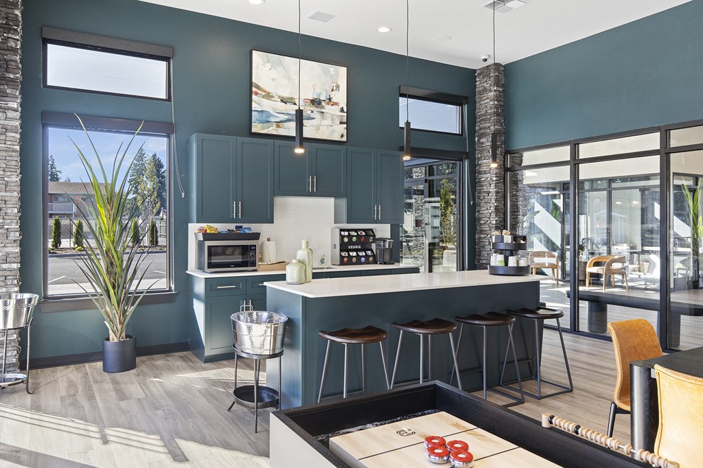 A modern kitchen with a bar stool and a potted plant.
