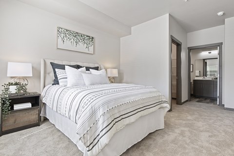A bedroom with a large bed and a painting on the wall.