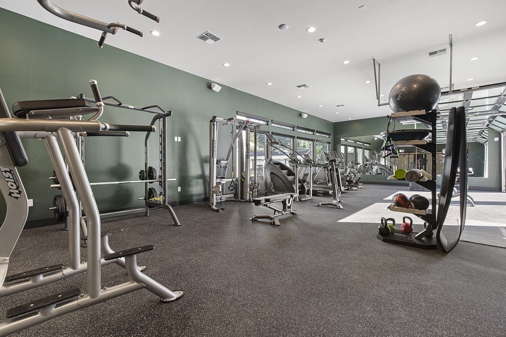 A gym with a variety of equipment including treadmills, weights, and exercise machines.