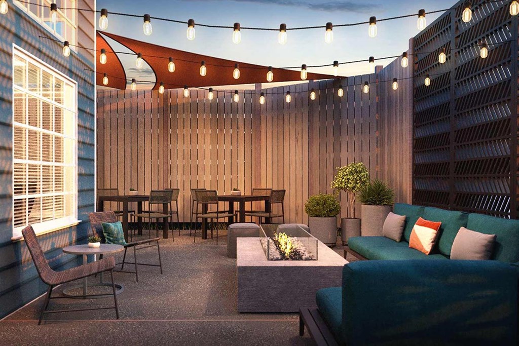 a patio with a couch and chairs and string lights