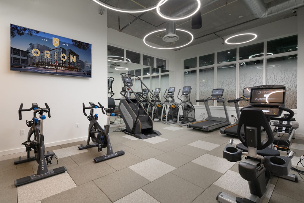 a gym with various exercise equipment and a tv on the wall