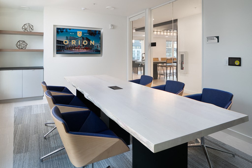 a conference room with a long white table and blue chairs