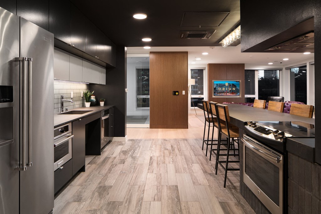 a kitchen with stainless steel appliances and a long counter with chairs