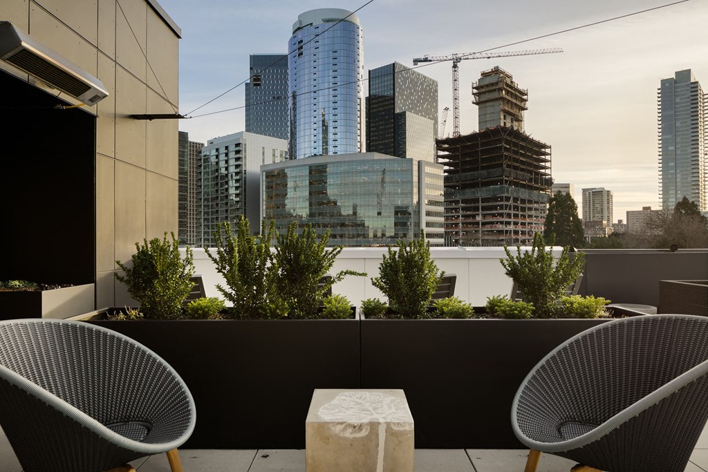 two chairs and a table on a balcony with a view of the city