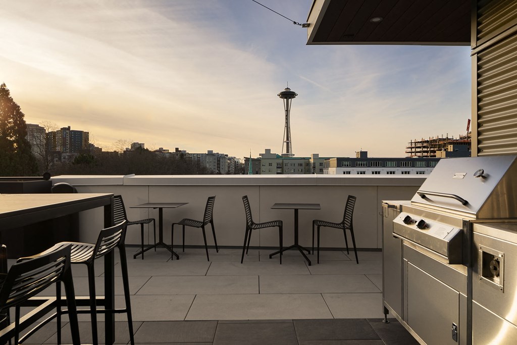 a balcony with a view of the city and a stove and chairs